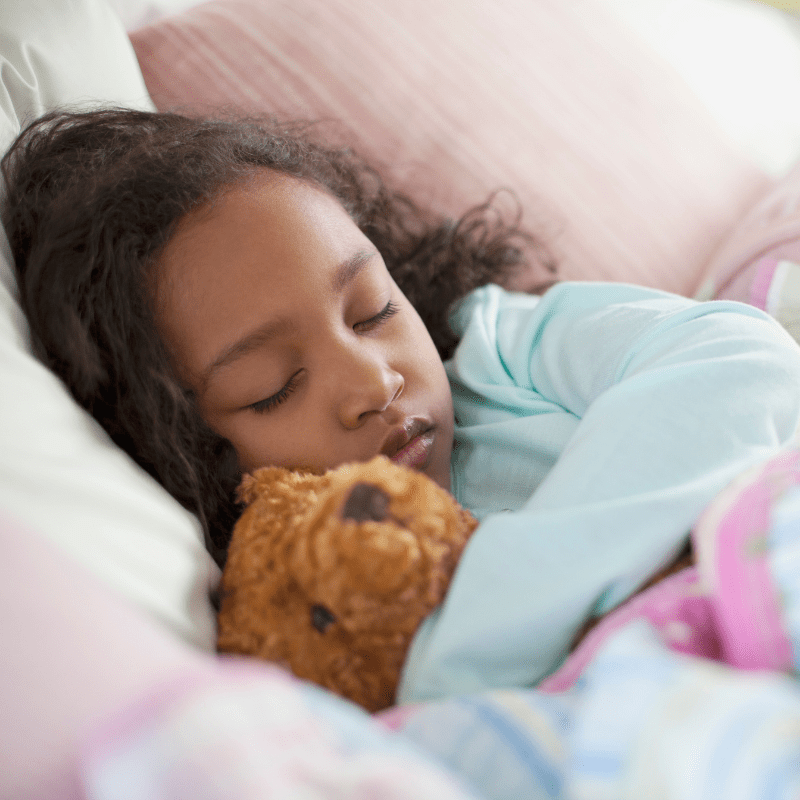 A girl sleeping with a stuffed toy